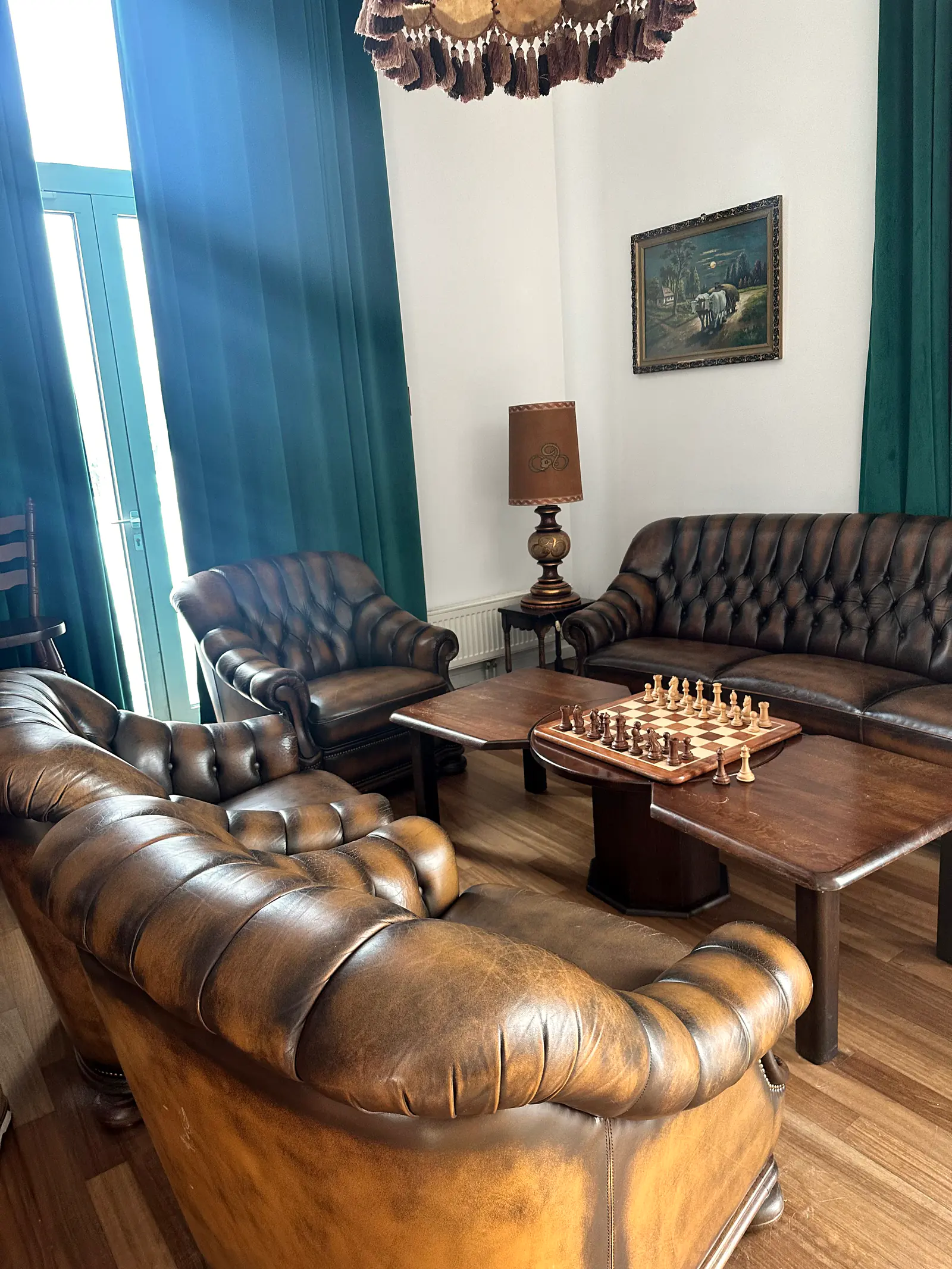Masă de șah între două canapele Chesterfield, lângă fereastra salonului