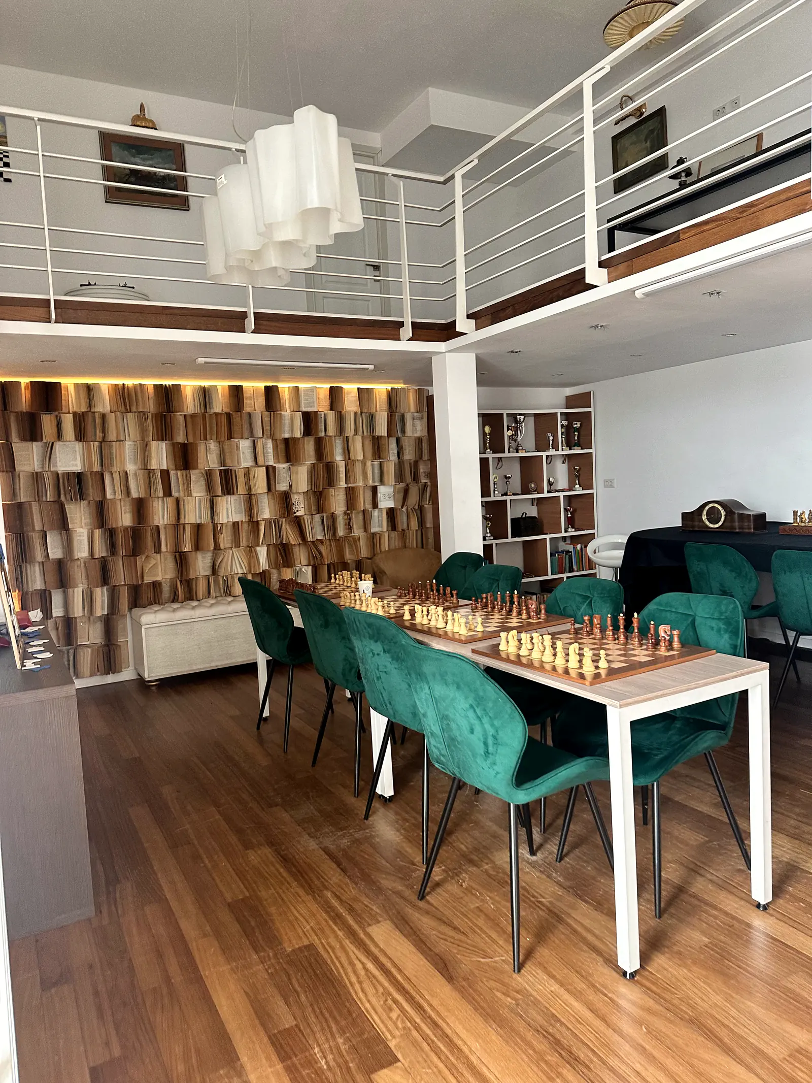 Sala de curs cu scaune de catifea verde și mese pregătite pentru partide